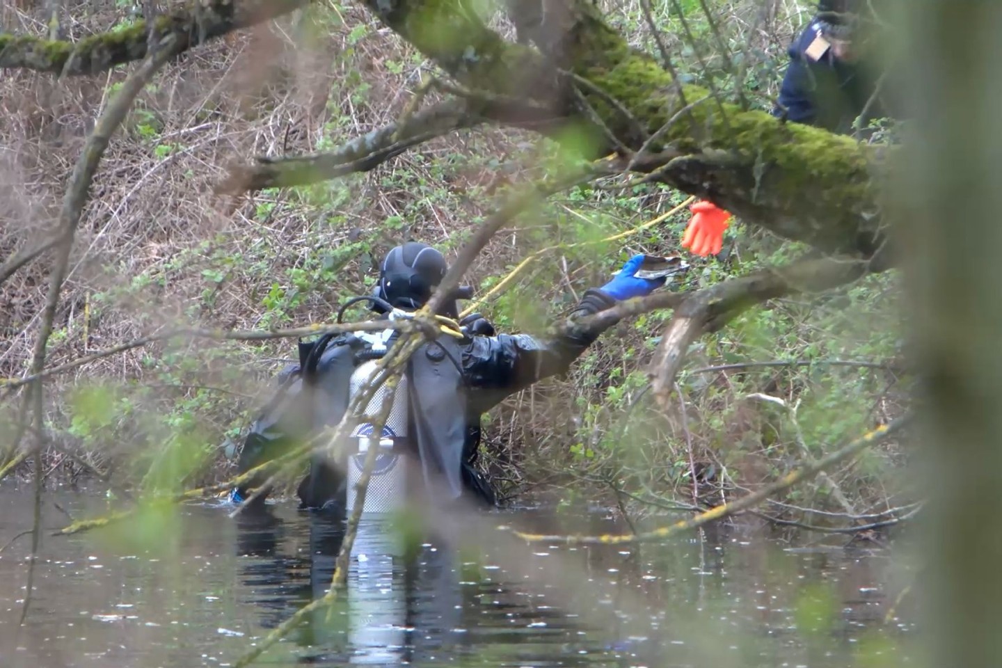Ein Taucher der Polizei sucht in einem Gewässer nach der Leiche einer mutmaßlich getöteten Frau.