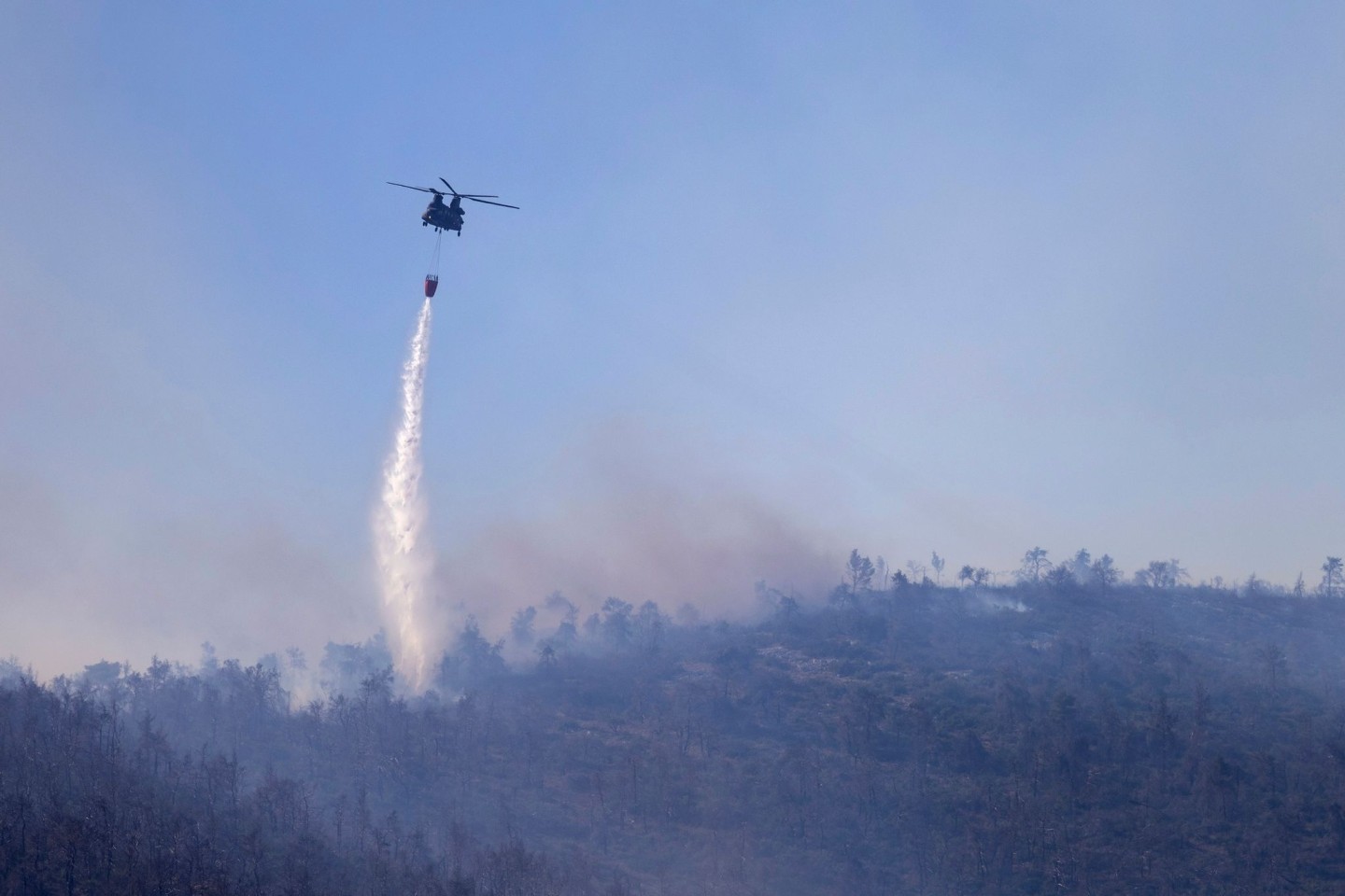 Ein Hubschrauber wirft Wasser auf einen Waldbrand im Norden Athens ab.