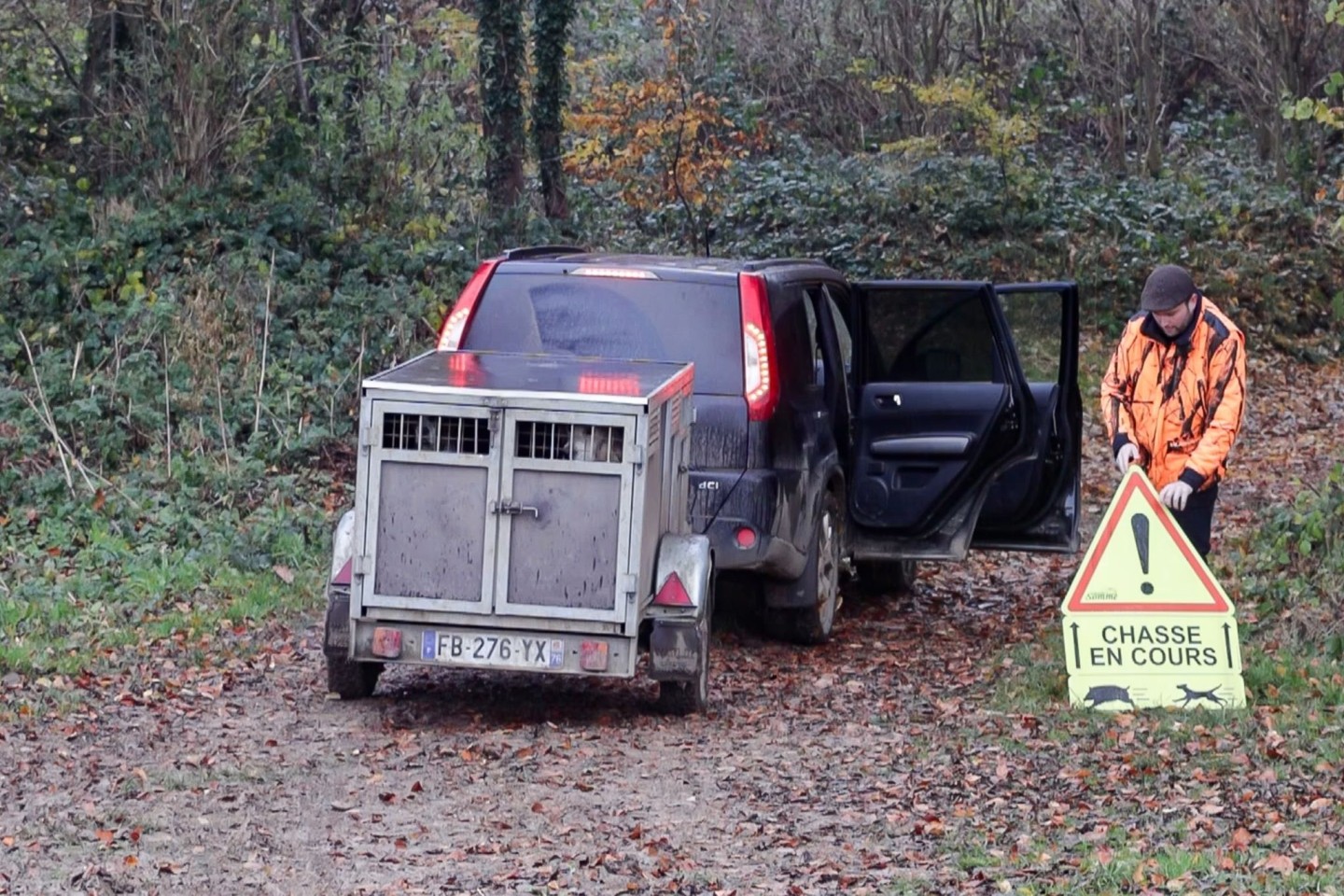 Ein französischer Jäger stellt ein Schild auf, das Spaziergänger vor einer Drückjagd warnt.